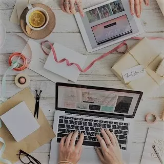 Une table avec des mains de personnes qui utilisent un ordinateur portable et une tablette tactile et du matériel de Do It Yourself.